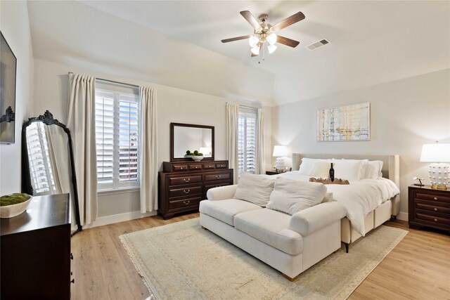 bedroom with a ceiling fan, visible vents, baseboards, light wood finished floors, and lofted ceiling