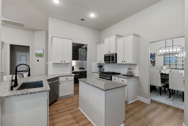 kitchen with visible vents, an inviting chandelier, a peninsula, a sink, and appliances with stainless steel finishes