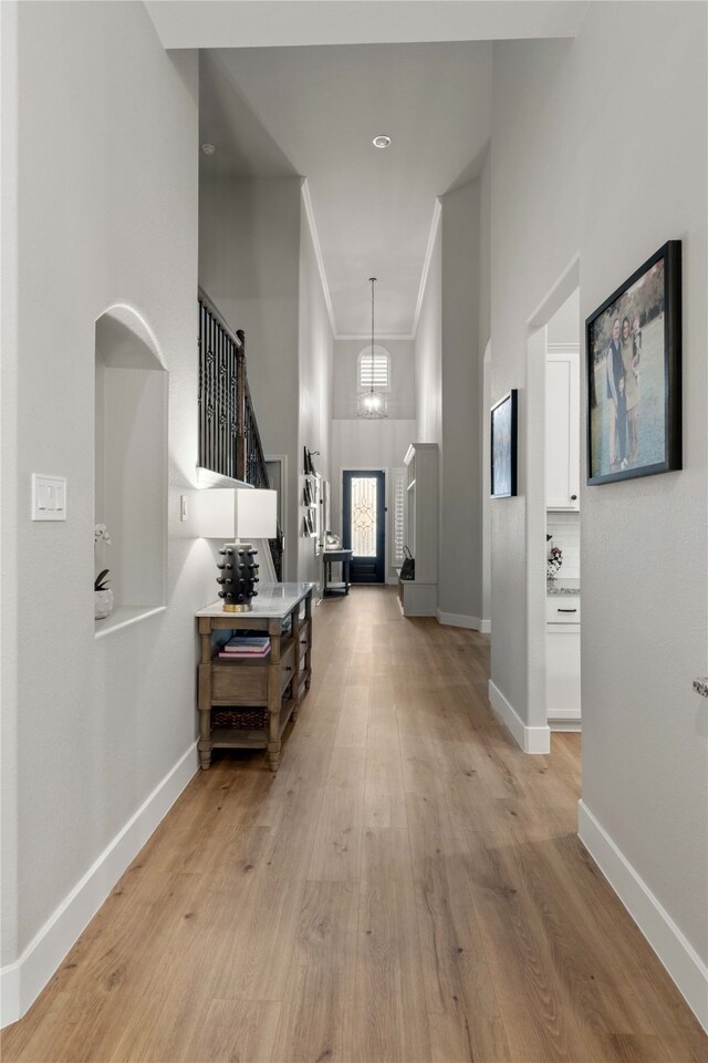 entrance foyer with a high ceiling, baseboards, and light wood-type flooring