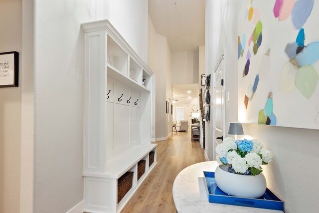 mudroom with baseboards, a high ceiling, and light wood-style flooring