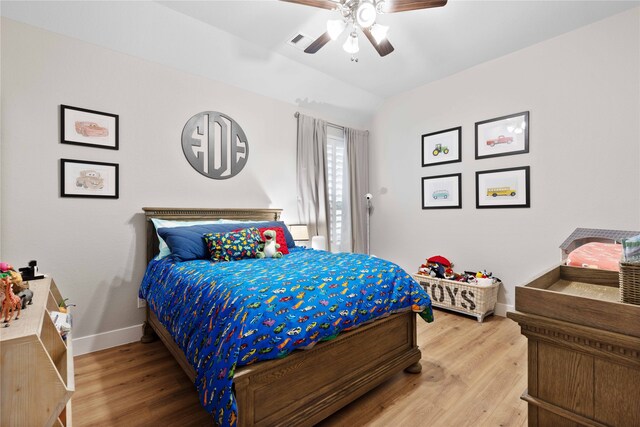 bedroom featuring visible vents, baseboards, ceiling fan, light wood finished floors, and vaulted ceiling