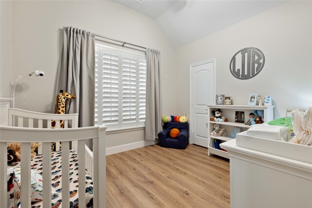 bedroom featuring light wood-style floors, baseboards, and lofted ceiling