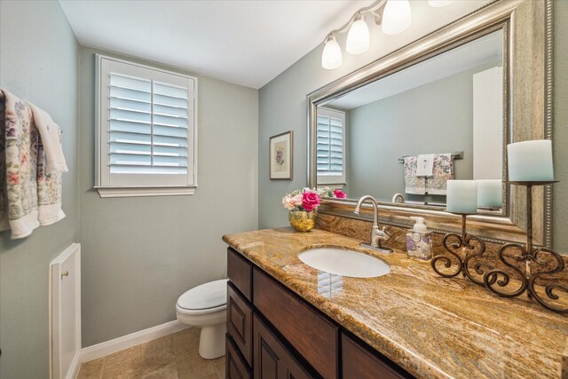 bathroom featuring toilet, baseboards, plenty of natural light, and vanity