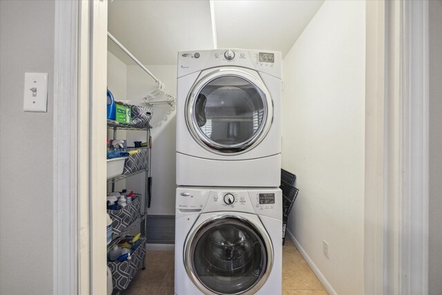 laundry room with laundry area, stacked washer / drying machine, baseboards, and tile patterned flooring
