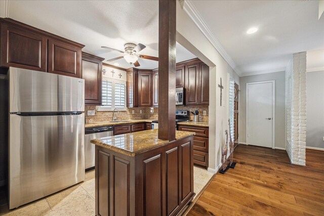 kitchen with ceiling fan, crown molding, appliances with stainless steel finishes, tasteful backsplash, and a sink