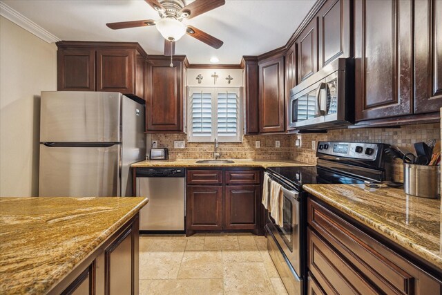 kitchen featuring decorative backsplash, ornamental molding, light stone counters, a sink, and stainless steel appliances