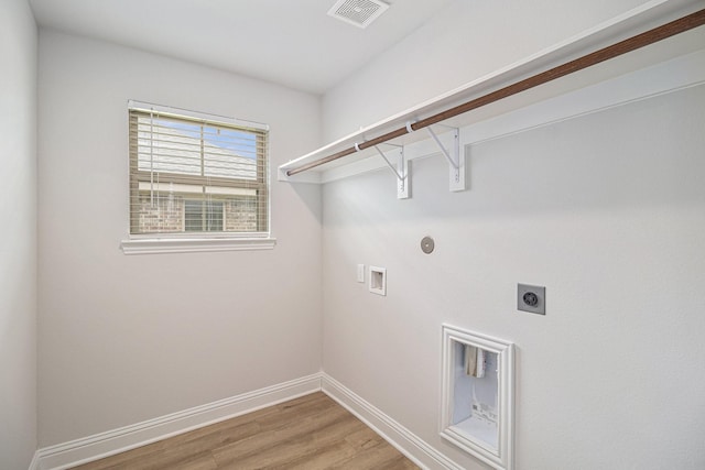 laundry room with laundry area, hookup for a washing machine, light wood-style flooring, electric dryer hookup, and visible vents