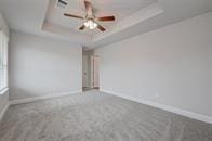 unfurnished room featuring baseboards, carpet, and a tray ceiling