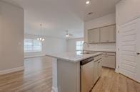 kitchen featuring dishwasher, light countertops, a kitchen island with sink, light wood-style floors, and open floor plan