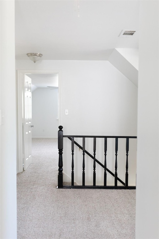 corridor featuring an upstairs landing, visible vents, and carpet floors