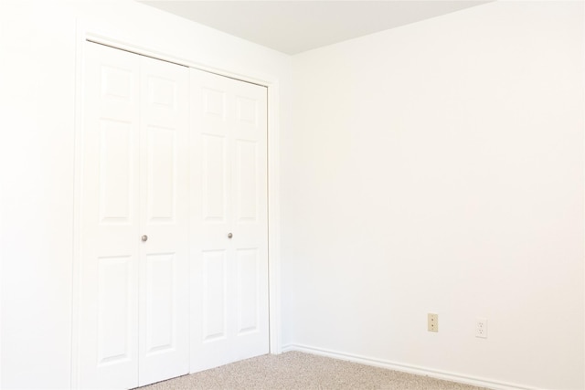 unfurnished bedroom with carpet floors, a closet, and baseboards