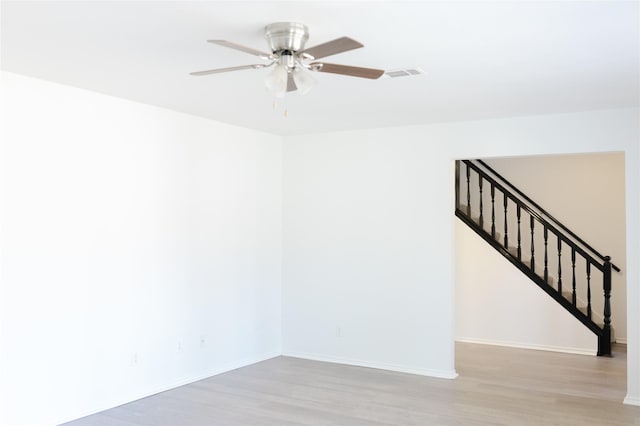 spare room with a ceiling fan, baseboards, and wood finished floors
