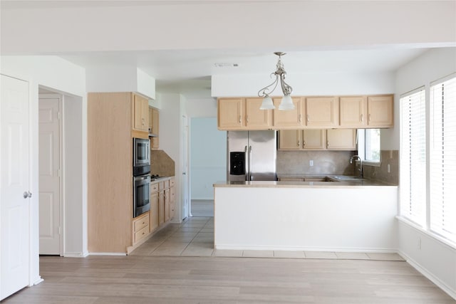 kitchen with light brown cabinetry, a healthy amount of sunlight, a peninsula, stainless steel appliances, and tasteful backsplash