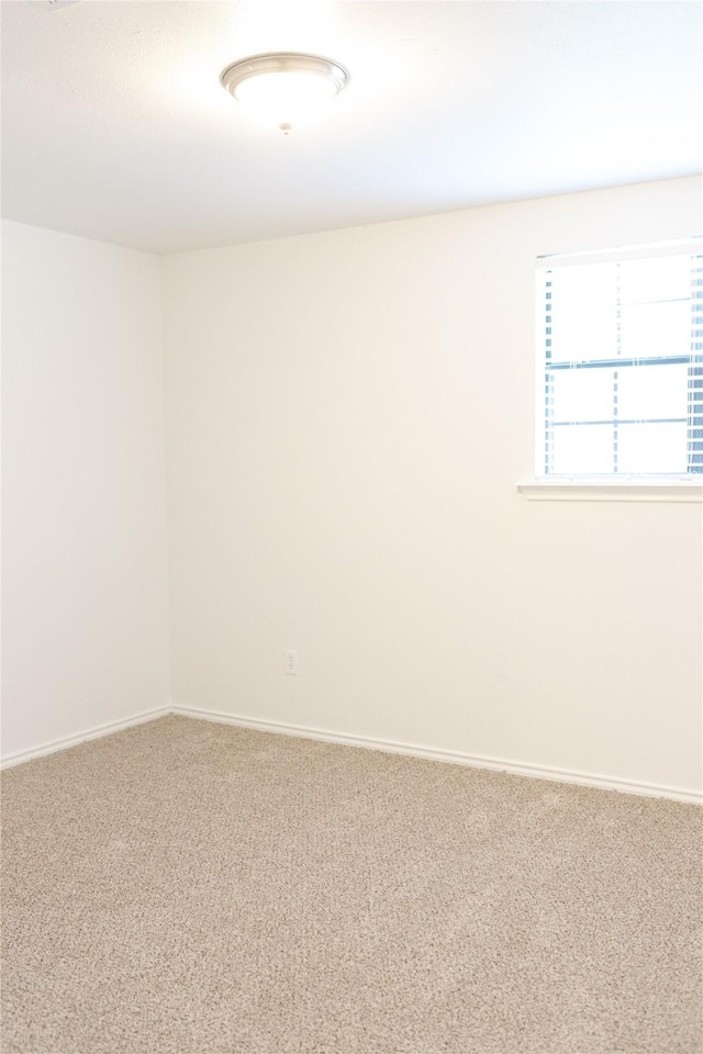 carpeted spare room featuring baseboards