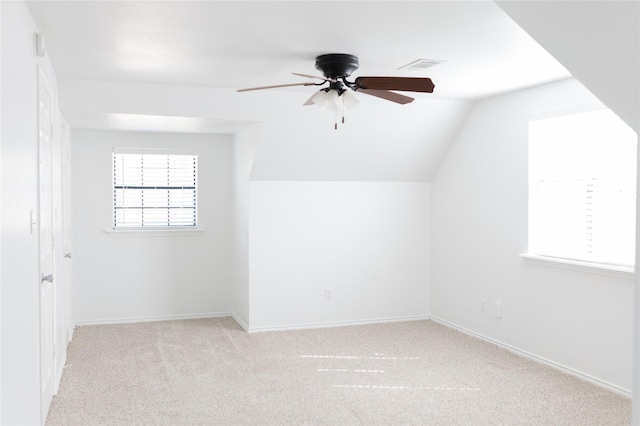 additional living space with visible vents, baseboards, ceiling fan, light colored carpet, and lofted ceiling