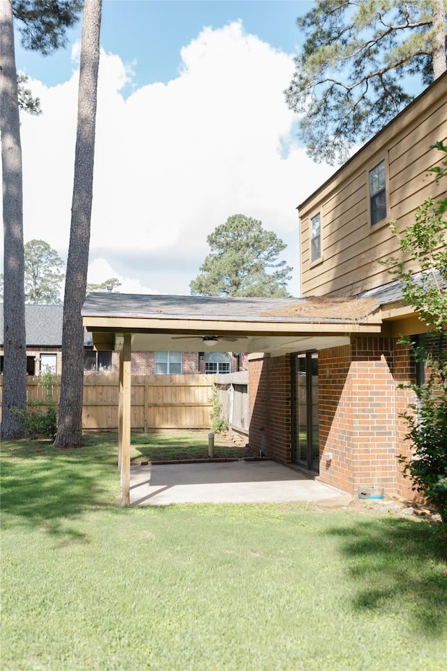 back of property featuring a lawn, brick siding, fence, a patio, and a carport