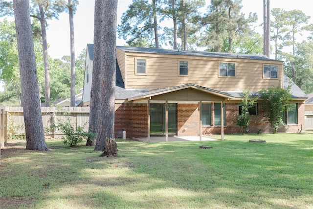 view of front of house with a patio area, a front yard, fence, and brick siding