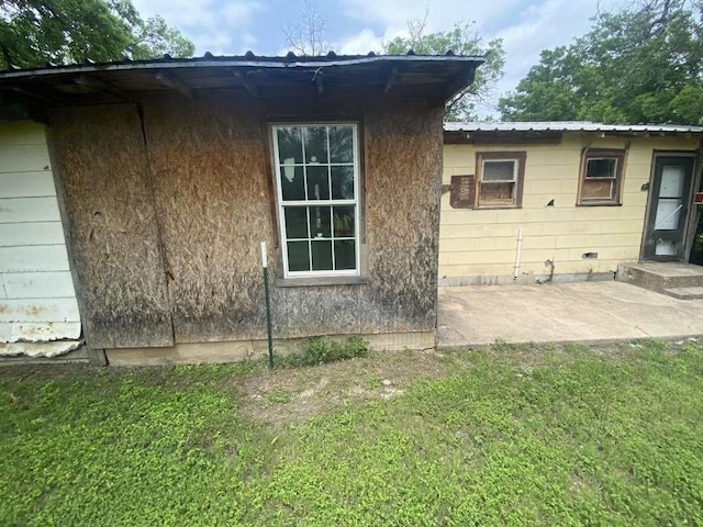 view of side of home with a patio, a yard, and metal roof