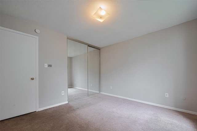 unfurnished bedroom with carpet floors, baseboards, and a closet