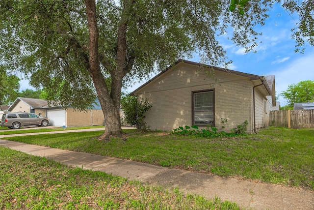 view of front of property featuring brick siding, fence, a front yard, and a garage