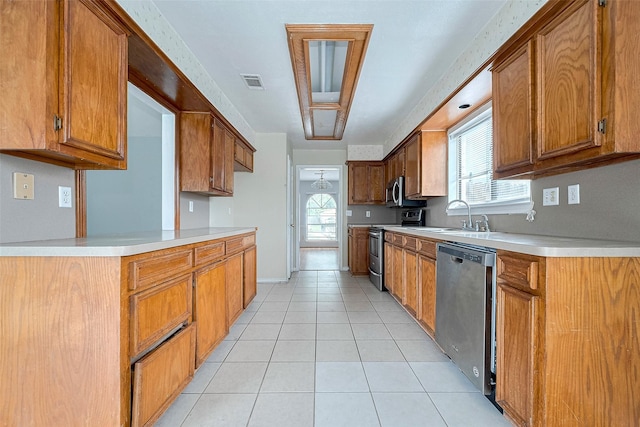 kitchen with brown cabinetry, a sink, and stainless steel appliances