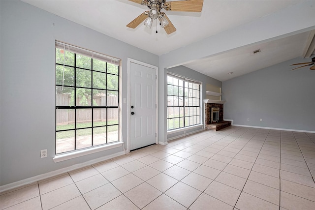 unfurnished living room featuring plenty of natural light, light tile patterned floors, ceiling fan, and baseboards
