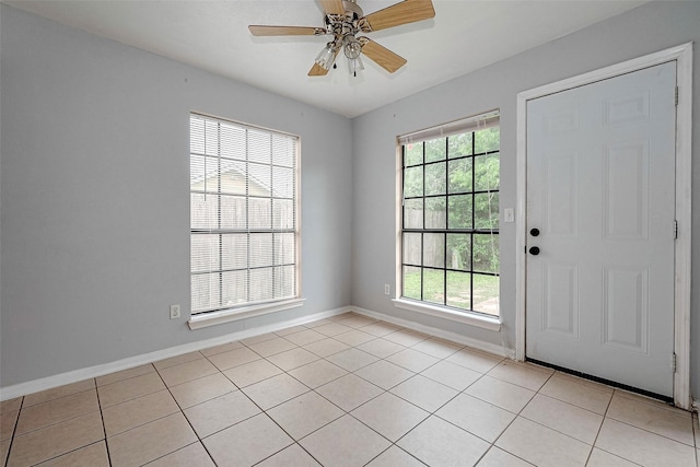 interior space with baseboards, ceiling fan, and light tile patterned flooring