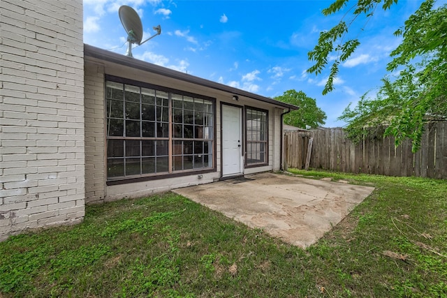 exterior space with a lawn, a patio area, fence, and brick siding