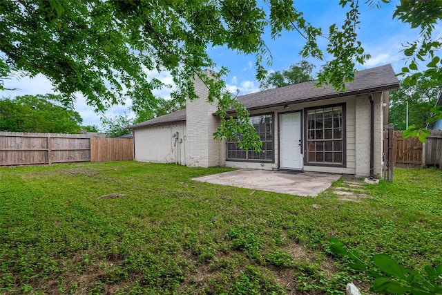 rear view of house with a fenced backyard, a patio, a lawn, and brick siding