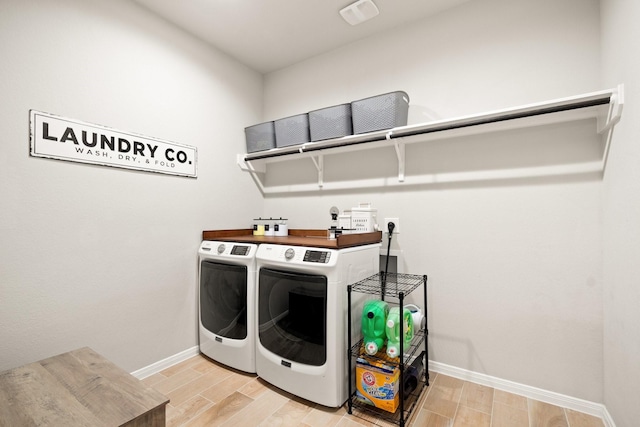 laundry room featuring baseboards, laundry area, washer and clothes dryer, and light wood-type flooring