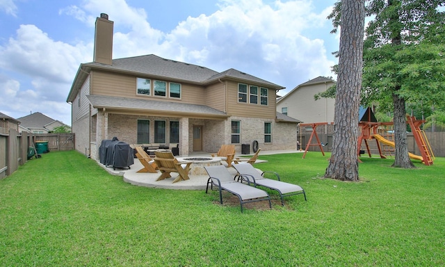 rear view of property with an outdoor fire pit, a fenced backyard, a chimney, a playground, and a patio