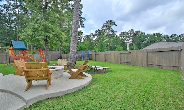 view of yard with a playground, a fenced backyard, a trampoline, and an outdoor fire pit