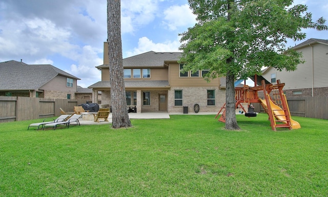 back of property with a patio area, brick siding, a fenced backyard, a playground, and a yard