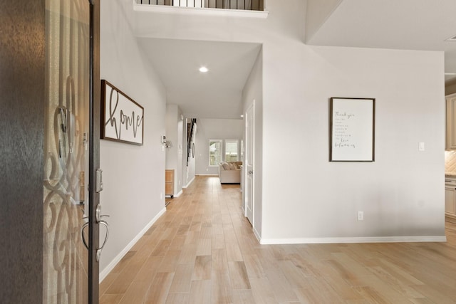 hall with recessed lighting, baseboards, and light wood finished floors