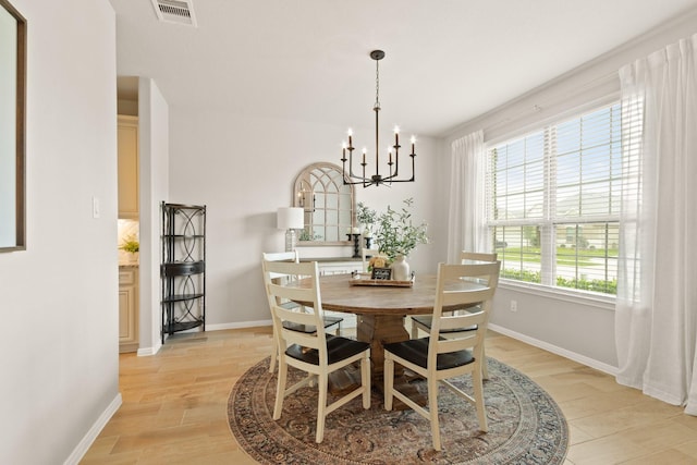 dining room with baseboards, a notable chandelier, light wood-style flooring, and visible vents