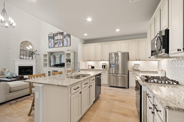 kitchen featuring a sink, appliances with stainless steel finishes, light wood-style flooring, and open floor plan
