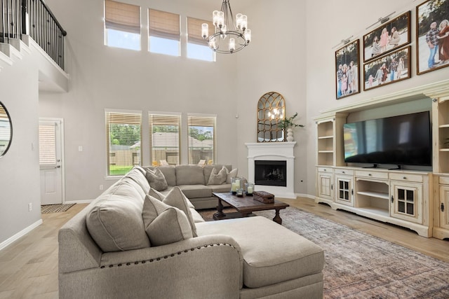 living room with baseboards, an inviting chandelier, light wood-type flooring, and a towering ceiling