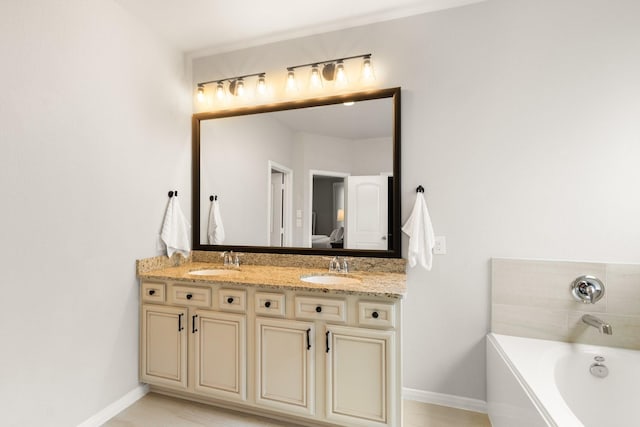 ensuite bathroom with a sink, baseboards, double vanity, and a bath