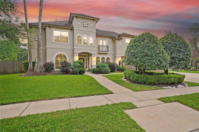 mediterranean / spanish home featuring fence, stucco siding, and a front yard