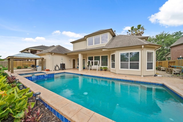 rear view of house featuring an in ground hot tub, a patio area, a gazebo, fence, and a fenced in pool