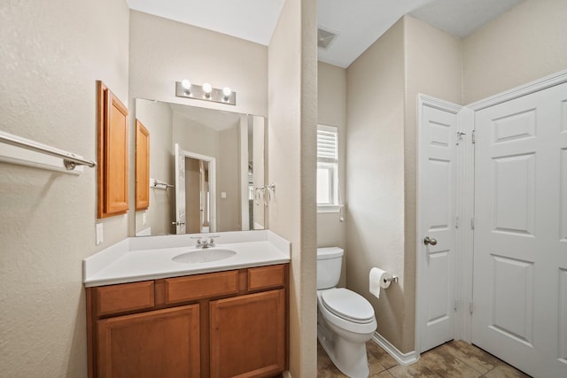 bathroom with visible vents, tile patterned flooring, vanity, toilet, and a textured wall