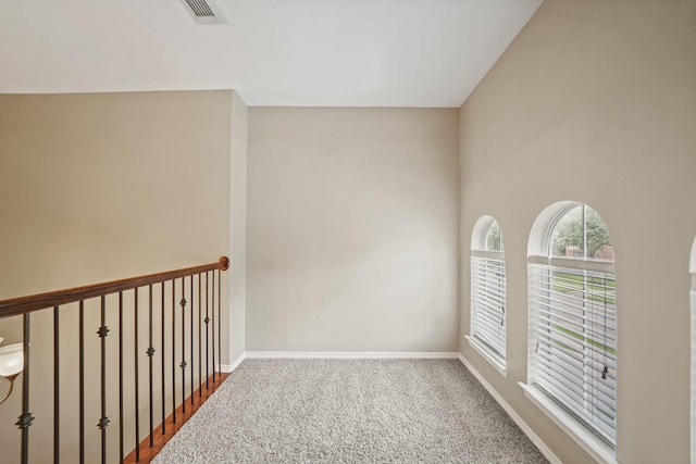 spare room with carpet flooring, baseboards, and visible vents