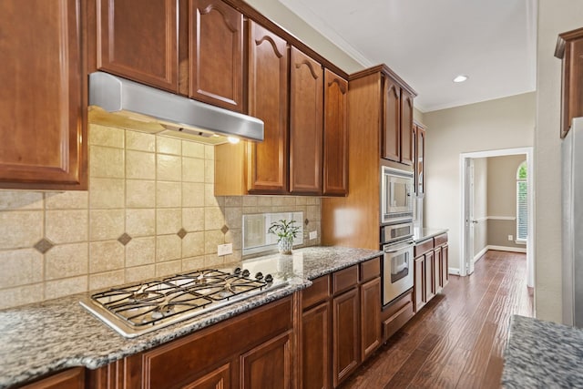 kitchen featuring light stone counters, dark wood-style floors, under cabinet range hood, ornamental molding, and stainless steel appliances