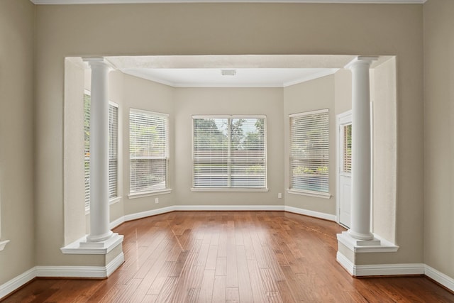 interior space with ornate columns, baseboards, and hardwood / wood-style flooring