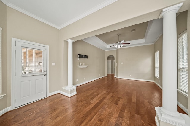 foyer featuring decorative columns, wood finished floors, baseboards, a raised ceiling, and a ceiling fan