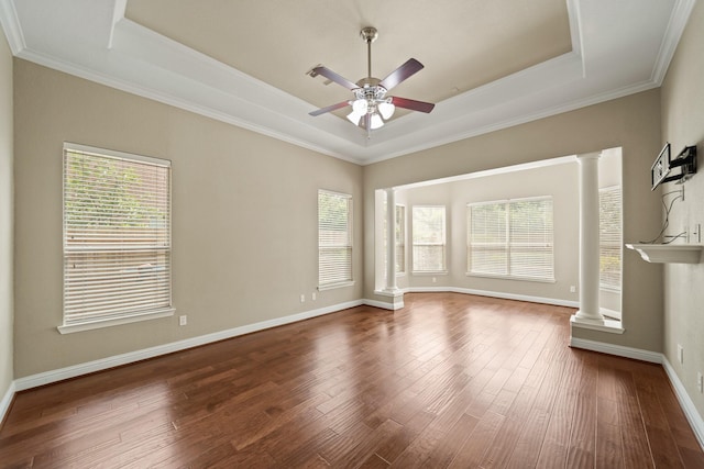 empty room with decorative columns, a wealth of natural light, and a raised ceiling