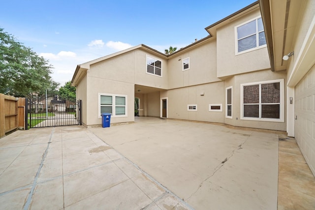 rear view of property with a patio, a gate, stucco siding, and fence