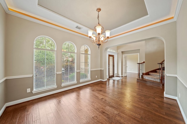 unfurnished dining area featuring arched walkways, a raised ceiling, and a notable chandelier