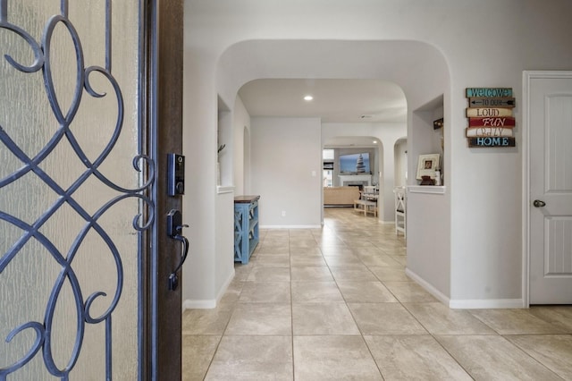 foyer entrance featuring arched walkways, baseboards, recessed lighting, and light tile patterned flooring