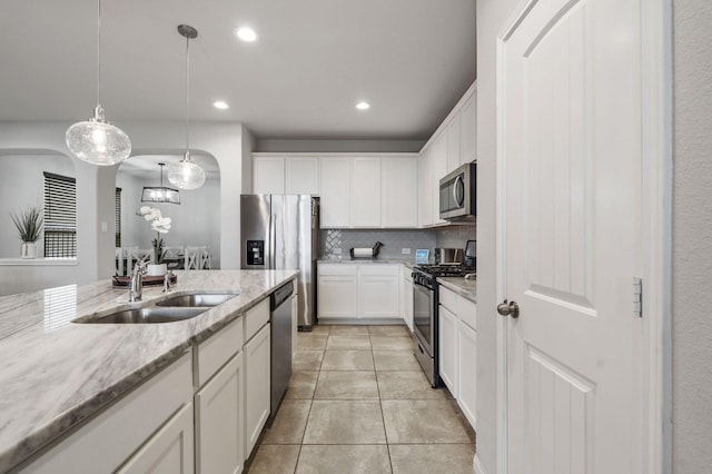 kitchen with a sink, tasteful backsplash, stainless steel appliances, and white cabinetry